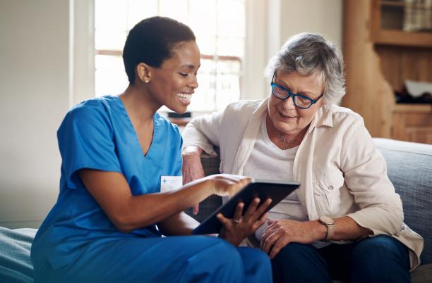 Carer with iPad and older woman