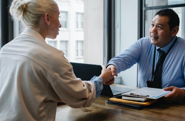 Man and woman shaking hands over a desk