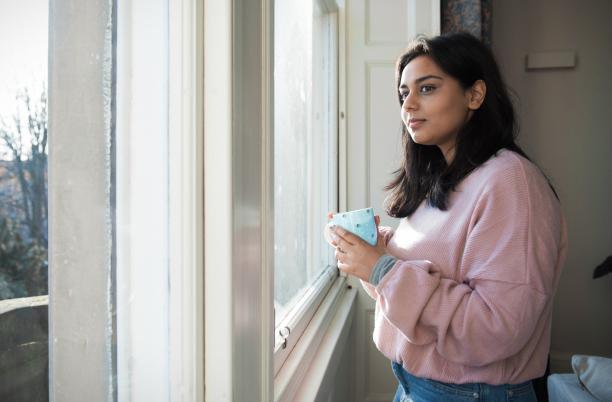 Dying Matters Resources from Hospice UK: a girl holding a coffee cup looks out of a window