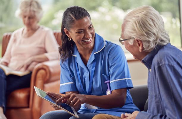 Hospice UK and Corndel launch Hospice Data Academy - image of nurse showing information to patient on and iPad