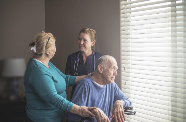Man in hospice looking out the window surrounded by hospice staff