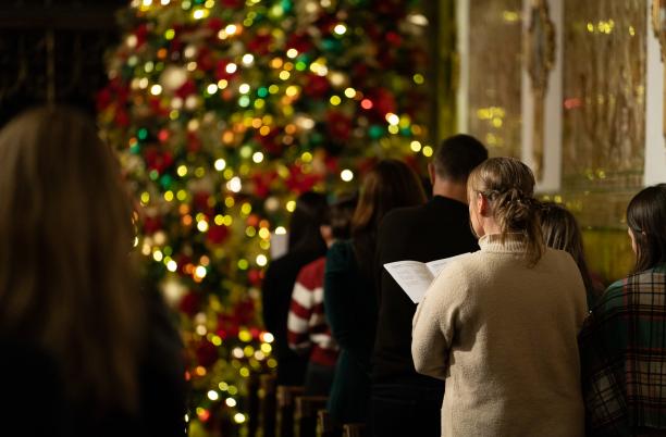 Woman singing carols by christmas tree