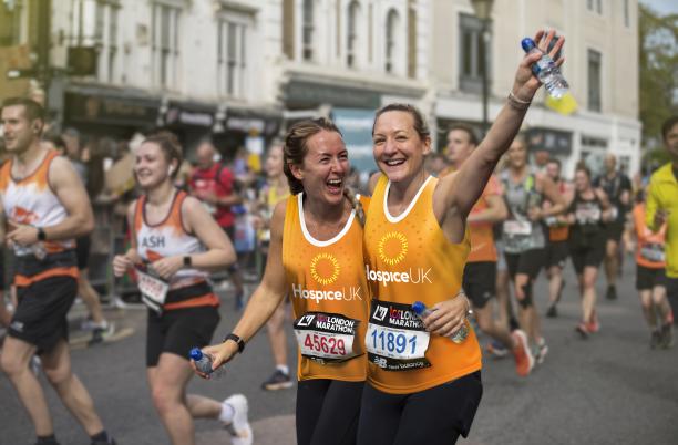 London Marathon 2025 - Two runners hugging and smiling wearing Hospice UK running vests