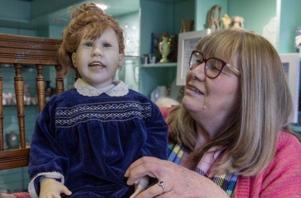 A lady with glasses holding a doll
