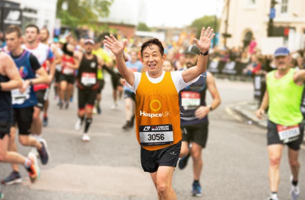 Runner in Hospice UK vest smiles and waves 