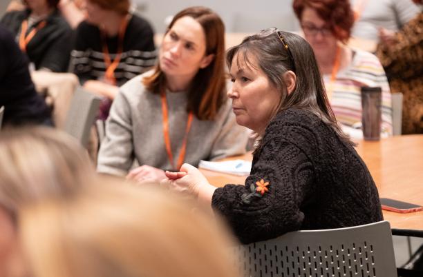 Two women seated at a table taking part in a conference session