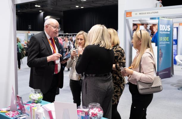 A group of people talking at an exhibition stand a the Hospice UK National Conference 2024