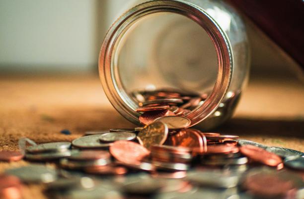 A stock photograph from Unsplash showng a jar tipped over, that had been filled with money