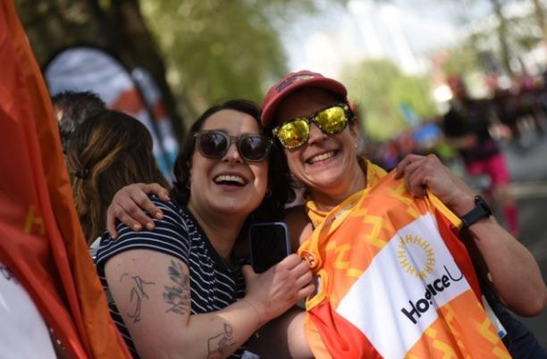 Two smiling supporters, holding up a Hospice UK running vest and embracing