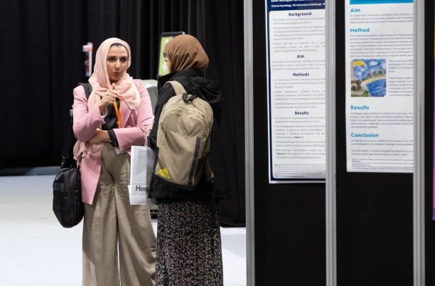 Two women having a conversation next to the poster exhibition at National Conference