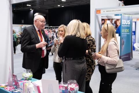 A group of people talking at an exhibition stand a the Hospice UK National Conference 2024