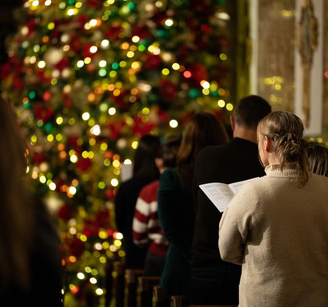 Woman singing carols by christmas tree