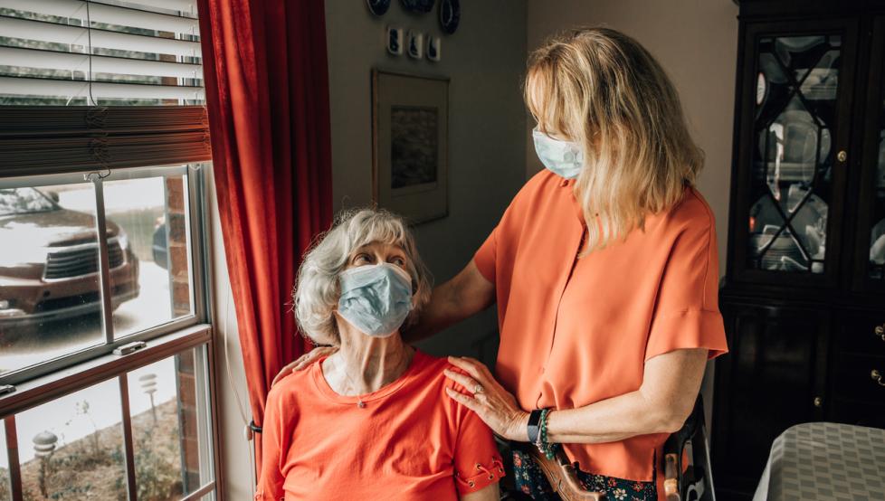 Daughter talking with her mother wearing protective mask