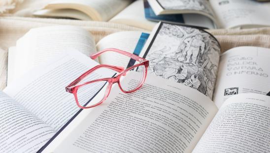 A stock image of a pair of glasses resting on a number of books