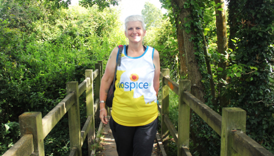 Female walking across countryside bridge in HospiceUK tshirt